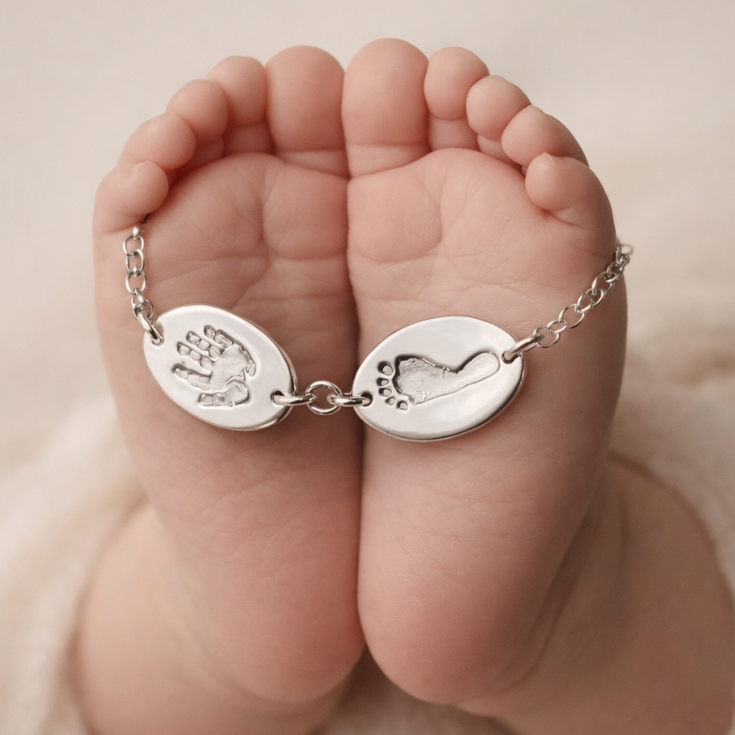 Baby's feet holding a bracelet with handprint and footprint on them