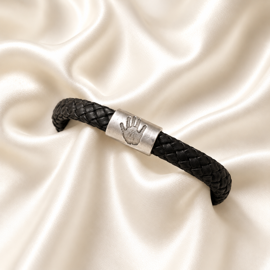 Handprint on a silver charm on a black leather bracelet