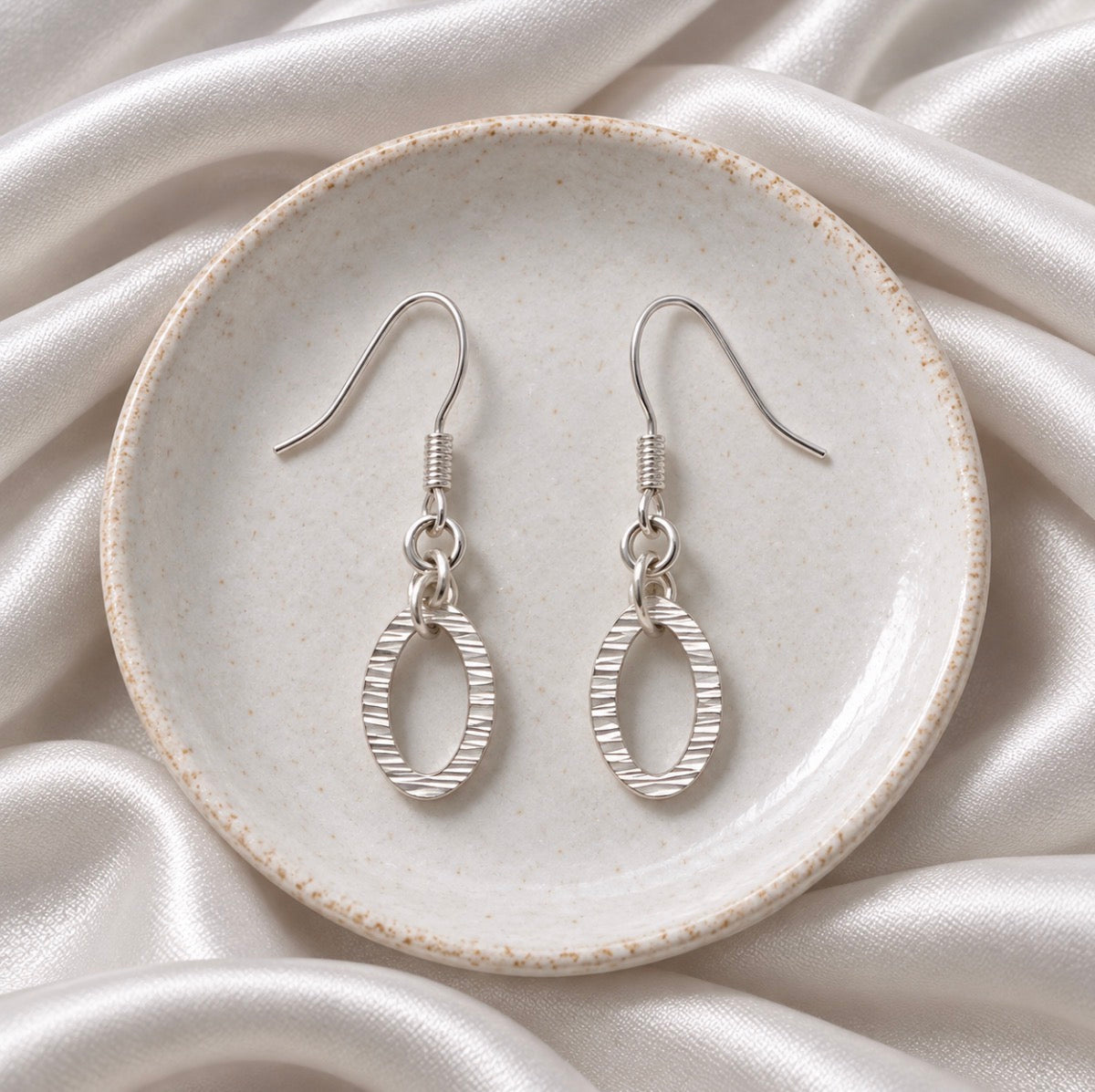 Oval silver drop down earrings with a hammer effect