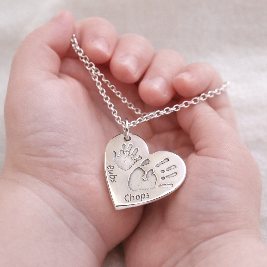 Personalised double handprint necklace held by a baby