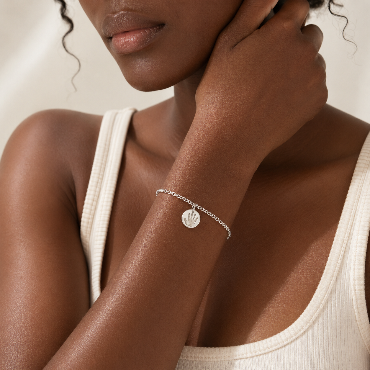 Lady wearing a personalised bracelet with a circle charm with a handprint on it.