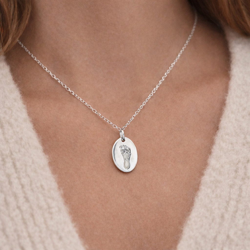 footprint on an oval silver pendant