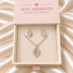 A silver leaf pendant necklace and matching stud earrings displayed in a light pink jewellery box. Made by Mini Memento