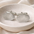 Oval cufflinks with fingerprints on them